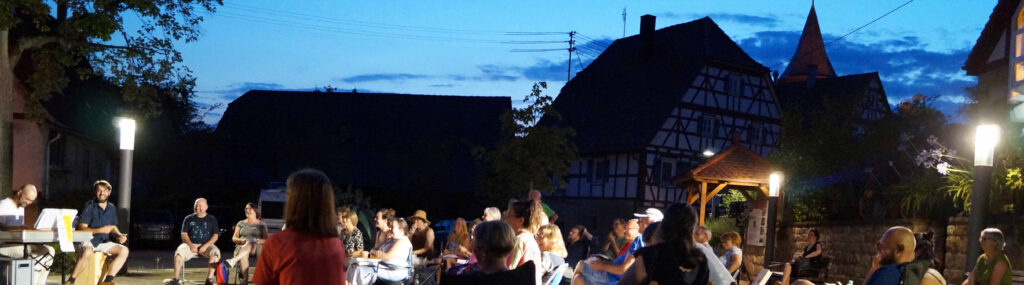 Auf dem Kelterplatz geht die Dämmerung in die Nacht über, wir singen weiter.
